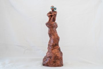 Fotografia de una escultura de barro de un niño sentado